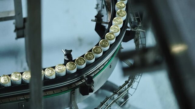 White and gold cans running through a conveyor system in a factory
