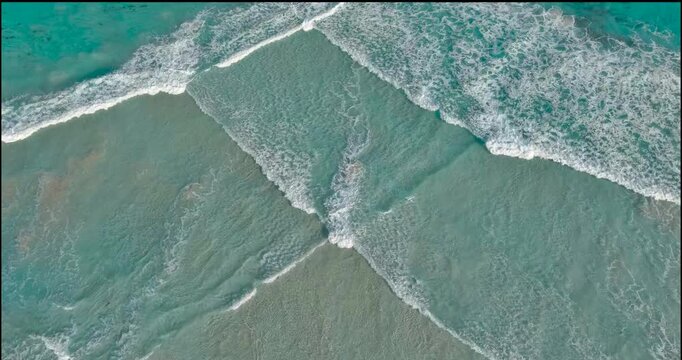 Crashing waves create unique patterns in the blue waters of Twilight Beach, Esperance. The waves wrap around and converge, making diamond shapes in the white foam.