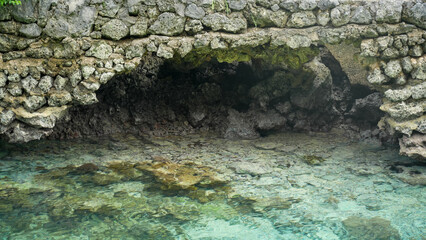 Clear turquoise water beneath natural stone wall cave