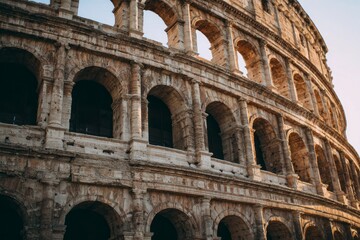 Obraz premium Ancient stone arches of a historic amphitheater glow in sunlight.