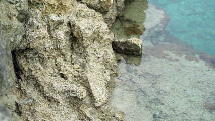 Rough coastal rock texture beside clear blue seawater