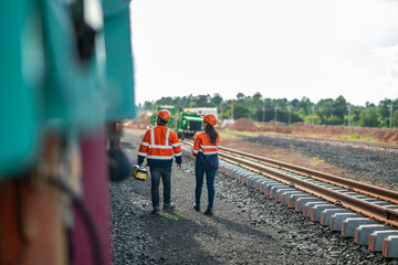Construction engineer inspecting railway track industrial documents in hand while examining rail...