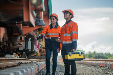 Construction engineer inspecting railway track industrial documents in hand while examining rail...