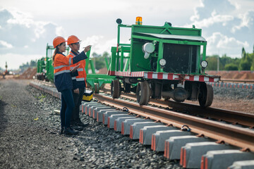 Construction engineer inspecting railway track industrial documents in hand while examining rail...