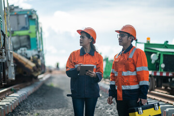 Construction engineer inspecting railway track industrial documents in hand while examining rail...