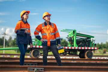Construction engineer inspecting railway track industrial documents in hand while examining rail...