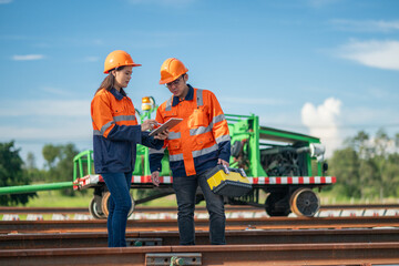 Construction engineer inspecting railway track industrial documents in hand while examining rail...