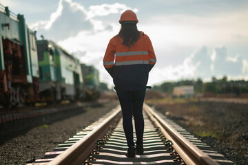 Construction engineer inspecting railway track industrial documents in hand while examining rail structure closely construction, safety and professional project management transportation development.