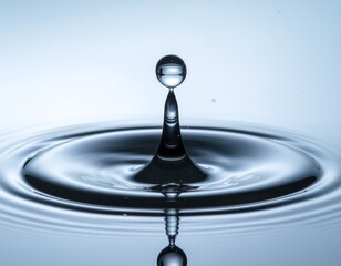 A perfect spherical water droplet captured mid-air above a splash, creating concentric ripples on a calm blue surface.