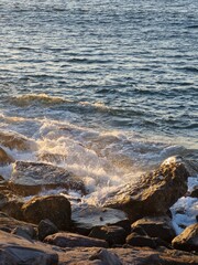 Golden hour waves crash on rugged rocks, creating a stunning coastal scene that evokes peace and tranquility, perfect for travel and nature themes