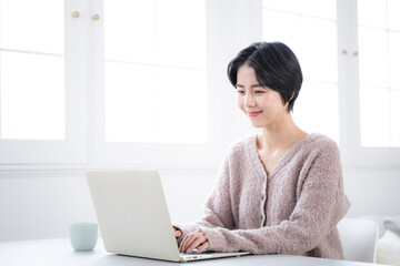リビングでパソコンを使うニットを着た女性