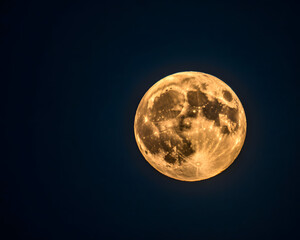 Majestic golden full moon illuminates deep night sky casting ethereal glow for celestial inspiration and cosmic wonder