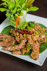 A delicious meal of Thai-style Larb and grilled meat, artfully presented on a white plate