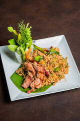 Delicious Asian dish served on a white square plate, top view shot with a brown background, the dish looks appetizing and tasty.