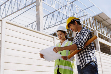 Asian engineers discussing building plans on a construction site, overseeing teamwork and future...