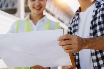 Construction engineers working as a team, holding and discussing a blueprint while planning at a...