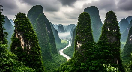 Fotobehang Guilin Dramatic karst mountain peaks covered in lush green vegetation with a winding river below under a cloudy sky  © Sadia