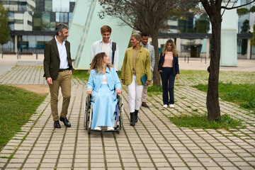 Diverse business team assisting woman in wheelchair