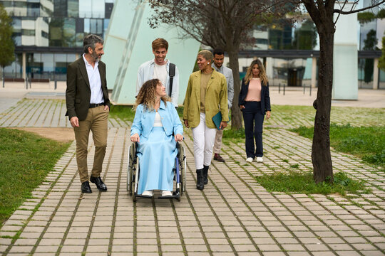 Diverse business team assisting woman in wheelchair