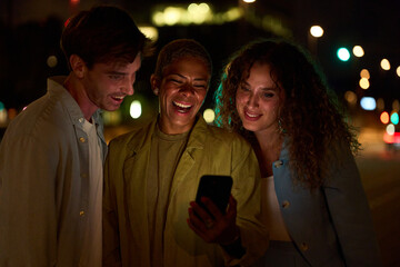 Diverse friends laughing enjoying mobile phone content