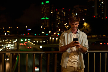 Young man using phone urban city night