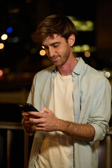 Young man using smartphone messaging at night