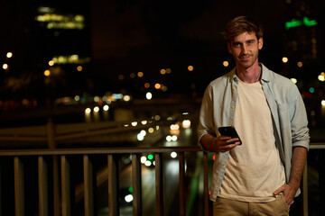 Young man using phone in urban night scene