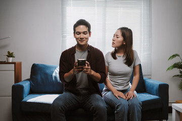 Jealous woman looking suspiciously at a man engrossed in his phone, suggesting relationship...