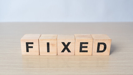 Fixed - word from wooden blocks with letters, fixed interest rates or costs concept, random letters...