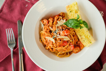 A delicious plate of spaghetti with meat sauce, cherry tomatoes, basil, and garlic bread, ready to be enjoyed
