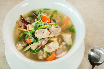 A bowl of delicious and flavorful Tom Yum soup, ready to be enjoyed. The soup is filled with chicken, vegetables, and herbs
