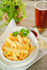 Delicious crispy golden french fries in a bowl, with sauces and a refreshing drink