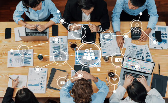 A diverse team collaborates at a modern workspace, surrounded by charts and devices, symbolizing connectivity and the integration of technology into business strategies. Amity