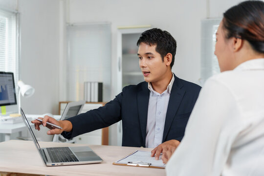Business man discussing data on a laptop with a female colleague during an office meeting, presenting financial analysis