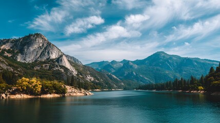 Obraz premium Expansive body of water winds between steep forested slopes and massive granite peaks under a bright sky