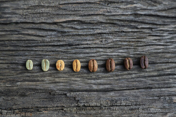 Color roast level of green coffee bean to dark roasted bean on wooden board. top view.
