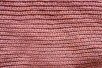 Fototapeta premium Close-up of soft pink knitted wool fabric with horizontal rows, showing texture and warmth in macro detail. Cozy textile background. Photo