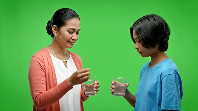 Caring Asian Mother Gives Medicine to Her Child on Green Screen.