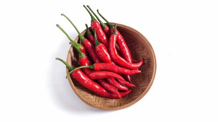Top view of Red hot chili peppers on bamboo bowl. Isolated on white background with copy space. Clipping path. Perfect for design element, spicy food concept or any commercial usages. 