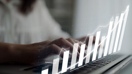 An individual works on a laptop, with a graph overlay representing business growth and financial success, showcasing modern workspace efficiency and technology use. Copula