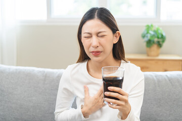 Acid reflux disease, suffer asian young woman, girl hand holding a glass of cola, have symptom...