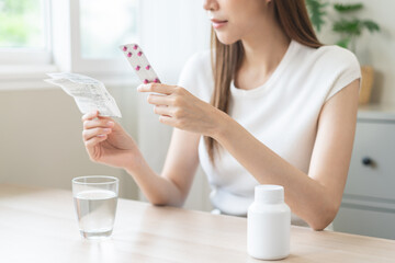Health care treatment asian young woman holding prescription of capsule medicine, reading label...
