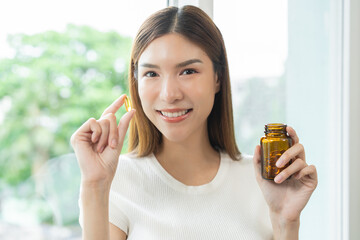 Dietary supplement concept, happy asian young woman hand holding fish oil pills, drugs medical...