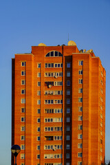 Sunset view of a modern brick apartment building against a clear blue sky in an urban setting