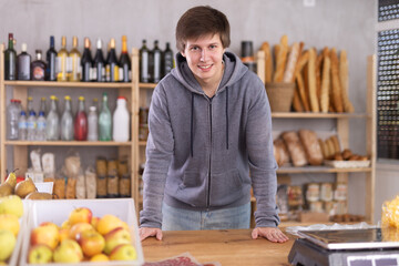 Courier in a gray sweatshirt in a supermarket. Smiling delivery man at a grocery store