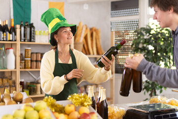 Female vendor in traditional Irish green cap offers Irish ale to male customer