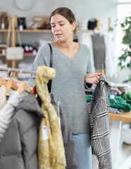 Female shopper selects clothes for autumn winter season in a clothing store