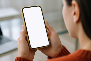 Woman holding smartphone with blank white screen in hands, close-up view, indoors with blurred background, wearing red sweater, technology concept. Ai generative