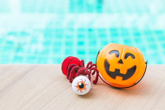 Red spider with eyeball and Halloween pumpkin lantern with space on swimming pool background, outdoor day light, Happy halloween background idea