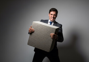 Businessman Carrying Heavy Concrete Block with Strained Expression